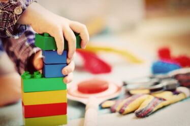 Kinderhände spielen mit bunten Legosteinen.